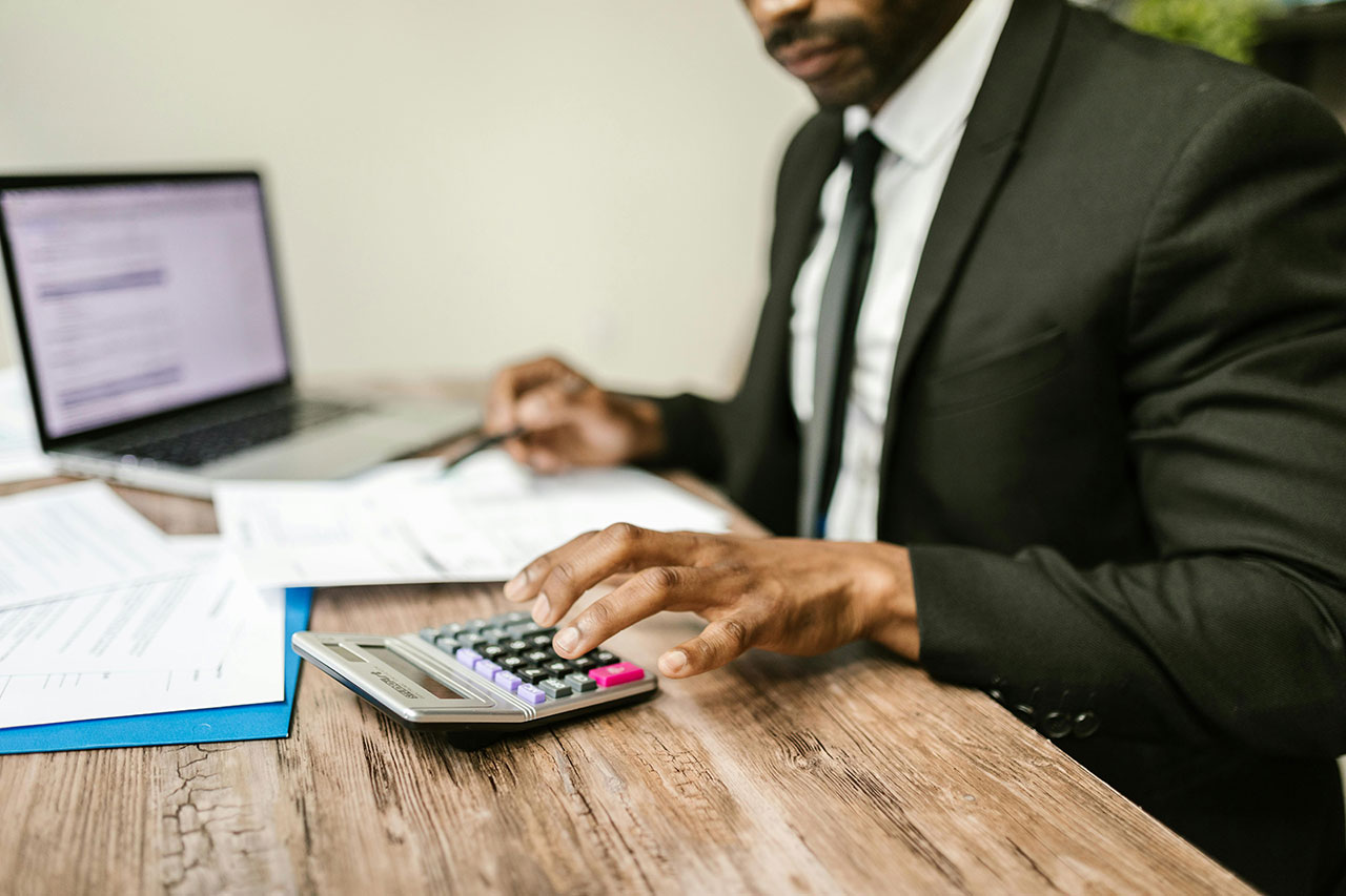 College and university CFO sitting at computer with calculator and revenue reports